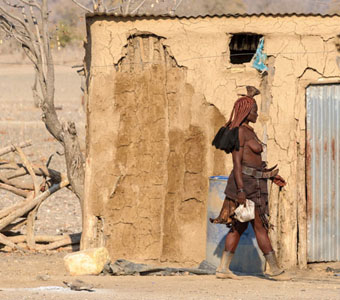 Himba Woman Walking In Front Of Her Home